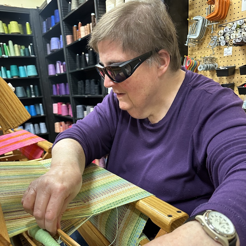 A resident sits at a loom in our Therapeutic Weaving Studio.